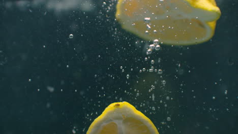 Several-lemon-fruits-fall-inside-a-water-tank-and-disturb-water.-Three-bright-yellow-lemon-fruits-fall-inside-a-water-tank-and-return-to-the-surface